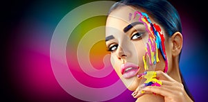 Beauty model girl with colorful paint on her face. Beautiful woman with flowing liquid paint