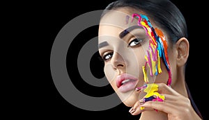 Beauty model girl with colorful paint on her face. Portrait of beautiful woman with flowing liquid paint