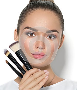 Beauty model girl, makeup artist holding set of make up brushes. Beautiful brunette young woman with perfect skin