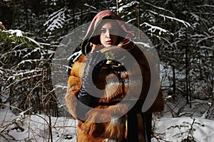 Beauty model girl in night winter forest. beautiful young Woman in fashionable Fur Coat and scarf