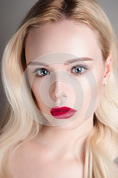 Beauty model girl with perfect make-up red lips and blue eyes looking at camera. Portrait of attractive young woman with blond hai
