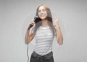 Beauty model girl singer with a microphone over light grey  background