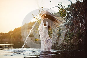 Beauty Model Girl Splashing Water with her Hair. Teen girl Swimming and splashing on summer beach.