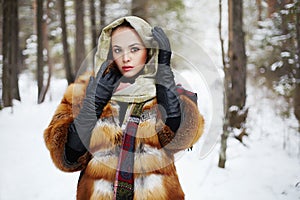 Beauty model girl in winter forest. beautiful young Woman in fashionable Fur Coat and scarf