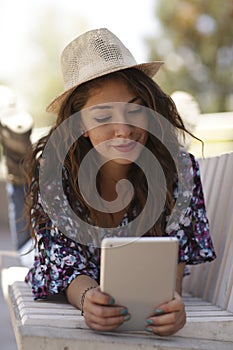 Beauty model with hat and using tablet in a park