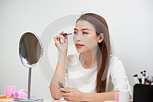 Beauty model teenage girl looking in the mirror and applying mas