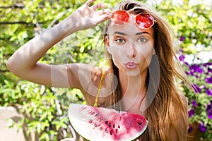 Beauty model with watermelon enjoy her vacation in flower tropical garden. Beautiful woman with red sunglasses