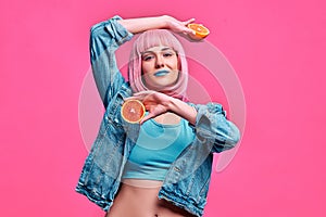 Beauty model woman holding juicy oranges over pink background