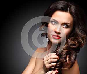 Beauty Model Woman with Long Brown Wavy Hair. Healthy Hair and Beautiful Professional Makeup. Red Lips and Smoky Eyes