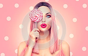 Beauty model woman with trendy pink hairstyle and beautiful makeup holding lollipop candy