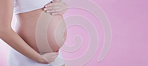 The picture of baby bump isolated on pink background. The happiness of waiting for a new family member.