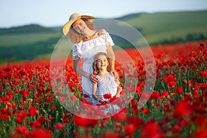 Beauty mother with teen enjoy summer days .Cute fancy dressed girl in poppy field. Field of blooming poppies.