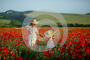 Beauty mother with teen enjoy summer days .Cute fancy dressed girl in poppy field. Field of blooming poppies.