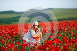 Beauty mother with teen enjoy summer days .Cute fancy dressed girl in poppy field. Field of blooming poppies.