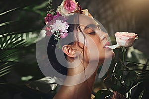Beauty, nature and flowers with a model woman biting a rose in studio on a natural forest background. Skincare, wellness