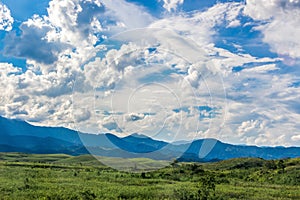 Beauty In Nature Summer Landscape. Amazing Blue Sky With Beautiful Clouds, Mountains, Field With Green Grass. Rural View In Rio.