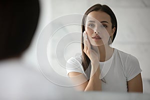 Pretty young lady cleansing face with lotion using cotton disc photo