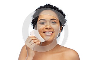 happy woman massaging her face with gua sha tool photo