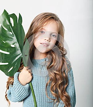 Beauty and fashion concept: Little curly girl child wearing blue sweater and holding flower