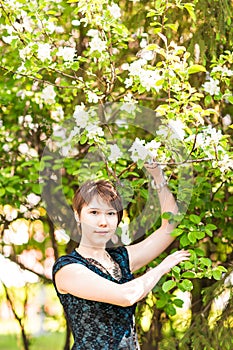 Beauty, people, summer and spring concept - beautiful young woman over green blooming garden background