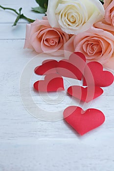Beauty pink-orange roses and red satin hearts shape on wooden floor. Valentine's day background concept