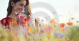 Beauty portrait of attractive brunette woman in a red dress in the field of flowers. White sky, sunny day and poppy