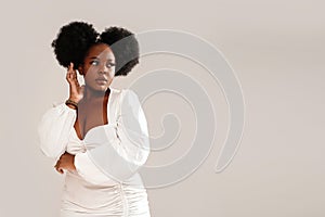 Beauty portrait of attractive woman with afro hairstyle and delicate makeup looking away, posing over studio background