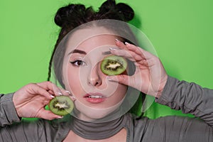 Beauty portrait of attractive young woman with clean radiant skin face with kiwi halves, brunette girl with bare