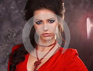 Beauty portrait of a beautiful brunette in a red dress on a gray background.