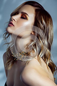 Beauty portrait of beautiful fashion model with makeup, colored wavy hairstyle and accessories on her neck.