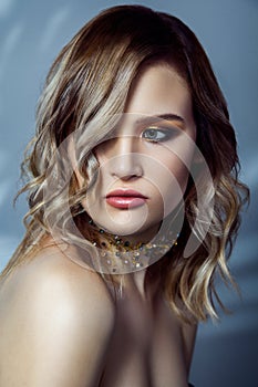 Beauty portrait of beautiful fashion model with makeup, colored wavy hairstyle and accessories on her neck.