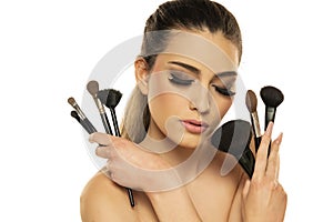 Beauty portrait of a beautiful sensual woman posing with make-up brushes