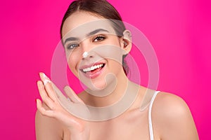 Beauty portrait of a beautiful woman applying face cream. Woman applying moisturizing skincare cream, lotion or mask for
