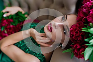 Beauty portrait. Beautiful woman with sensual maroon lips lying among peony flowers. Cosmetics, make-up. Perfumery