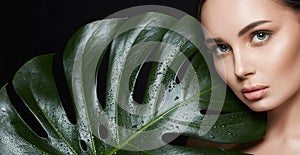 Beauty Portrait of brunette girl in palm leaves. Beautiful young woman with Make-up