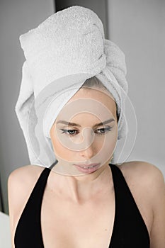 Beauty portrait of a cheerful attractive woman with a towel on her head and looking at camera, lying on bed.