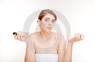 Beauty portrait of confused young woman choosing between two parfums