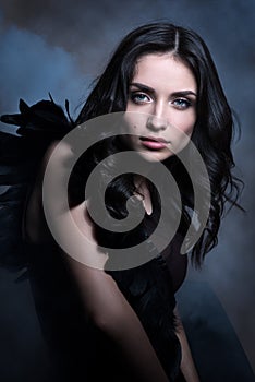 Beauty portrait in cool tones. Beautiful young woman in a dark way in the cloud of smoke