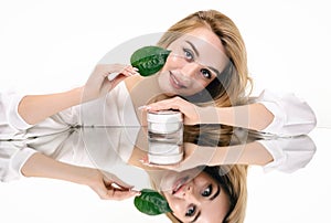 Beauty portrait with cosmetic cream and green leaf. Skin care and organic cosmetics concept