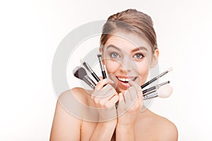 Beauty portrait of cute lovely young woman holding makeup brushes