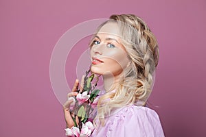 Beauty portrait of female face with natural skin. Attractive woman with makeup, blonde hair and flowers