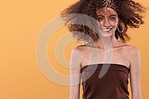 Beauty portrait of girl with afro hairstyle. Girl posing on yellow background, looking at camera, smiling. Studio shot