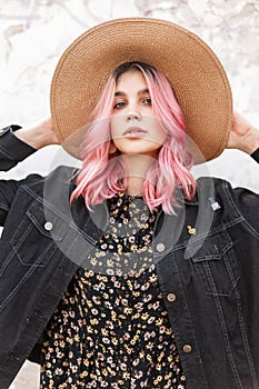 Beauty portrait gorgeous young woman with glamour pink hair in stylish denim casual jacket near wall on street. Lovely girl