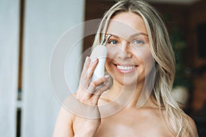 Beauty portrait of happy blonde smiling woman 35 year with clean fresh face and hands with long hair doing fasial massage with