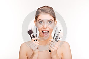 Beauty portrait of happy excited young woman with makeup brushes