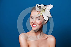 Beauty portrait of happy woman with the lily flower on blue