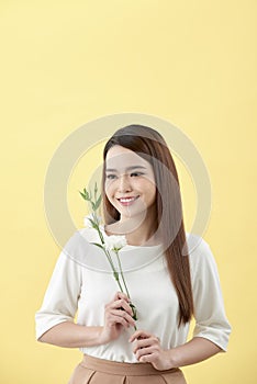 Beauty portrait of lady 20s holding white lisianthus flowers over yellow background