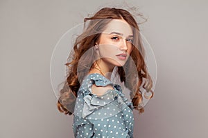 Beauty portrait of sexy young woman with messed up long curly hair looking seductively at camera, fashion model