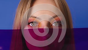 Beauty portrait shot. Young caucasian woman with make up and red film gel in front of her face. Copy space