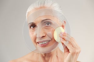 Beauty portrait of a smiling half naked elderly woman using make